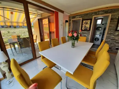 a dining room with a white table and yellow chairs at Mountain Villa near Bansko in Razlog