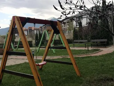 a wooden swing set in a park at Студио за трима, басейн, Aspen Golf Resort, Банско, Разлог in Razlog
