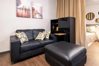 a living room with a black leather couch and a ottoman at Bohemia - New Apartment with Stylish Design in Sofia