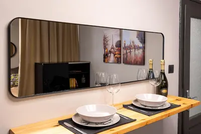 a mirror above a table with plates and wine glasses at Bohemia - New Apartment with Stylish Design in Sofia