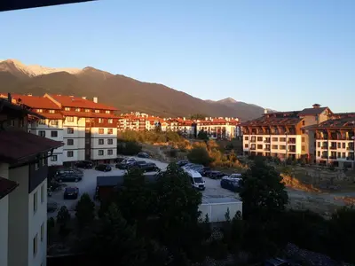 a city with buildings and a parking lot with mountains at Старият Хан-Б24 in Bansko