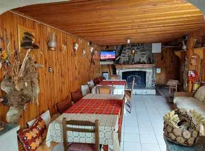 a living room with a table and a fireplace at Къща за гости Иглика in Trigrad
