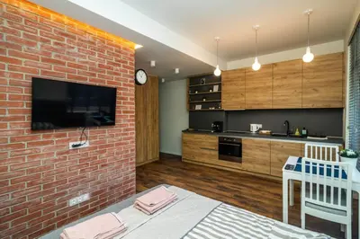 a living room with a brick wall and a kitchen at Exclusive Top Central Studio in Sofia