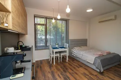 a bedroom with a bed and a table and a kitchen at Exclusive Top Central Studio in Sofia