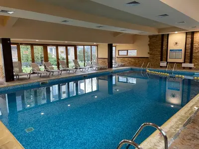 a large swimming pool with chairs in a building at Lovely 2-bedroom serviced apartment with SPA in Bansko