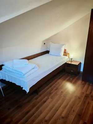 a bedroom with a bed with white sheets and a wooden floor at Дом Бакалски-Кмета in Narechenski Bani