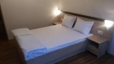a bed with white sheets and pillows in a room at Дом Бакалски-Кмета in Narechenski Bani