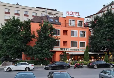 a hotel with cars parked in a parking lot at Hotel Geppy in Sofia