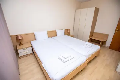 a bedroom with a large white bed and a chair at Hotel Astra in Sandanski