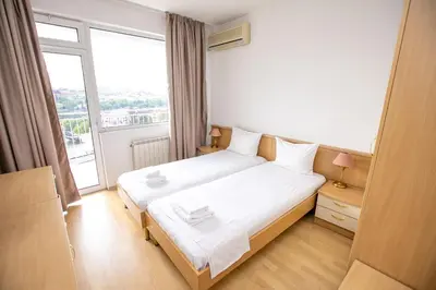 a bedroom with a white bed and a large window at Hotel Astra in Sandanski