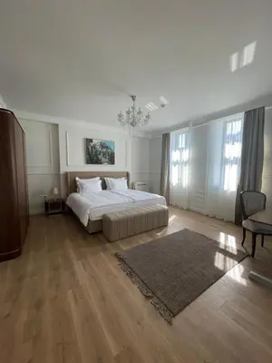 a large white bedroom with a bed and a chandelier at FELIX KANITZ Apartments - in the heart of Kapana district in Plovdiv