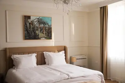a bedroom with a bed with white sheets and a chandelier at FELIX KANITZ Apartments - in the heart of Kapana district in Plovdiv