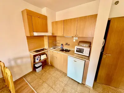 a kitchen with wooden cabinets and a white refrigerator at Todorini Kuli Apartments in Bansko