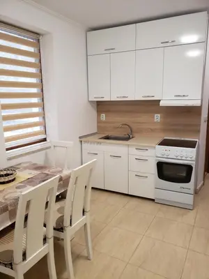 a kitchen with white cabinets and a table with chairs at Ski-in ski-out Studio 2A7 Grand Monastery in Pamporovo