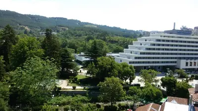 a large white building in a city with trees at Парк Апартаменти Юлия in Sandanski