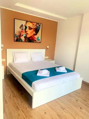 a bedroom with a large bed with a painting on the wall at Stella Guesthouse in Sapareva Banya