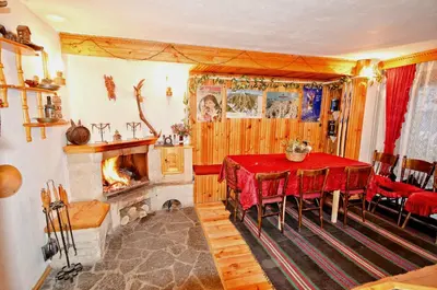 a dining room with a table and a fireplace at Palyongov Guest House in Chepelare