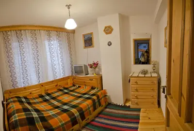 a bedroom with a bed and a dresser and a television at Palyongov Guest House in Chepelare