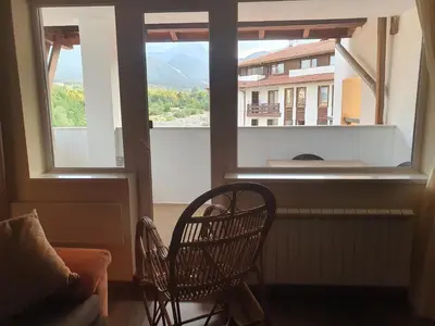 a room with two chairs and a large window at Family apartment VYANI in Bansko