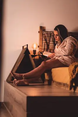 a woman sitting on a bed reading a book at Dakota forest retreat in Tsigov Chark