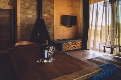 a wooden table with two glasses and a bottle of wine at Dakota forest retreat in Tsigov Chark