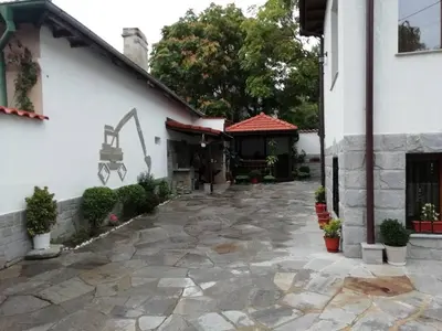 a courtyard of a white house with a stone driveway at Къща в центъра на Стрелча, джакузи с минерална вода in Strelcha