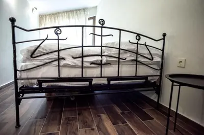 a black metal bed in a room with a wooden floor at ТАНГЕНТА стаи за гости in Oreshak