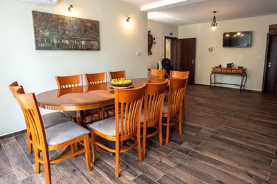 a dining room with a wooden table and chairs at ТАНГЕНТА стаи за гости in Oreshak