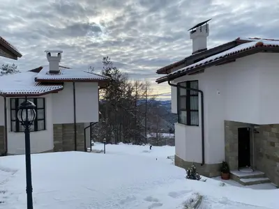 a house with snow in front of it at Cassiopea Villas in Pamporovo