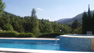 a swimming pool with a water fountain in front of a mountain at Hotel Perfect in Yamna