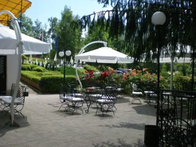 a patio with tables and chairs and an umbrella at Hotel Perfect in Yamna