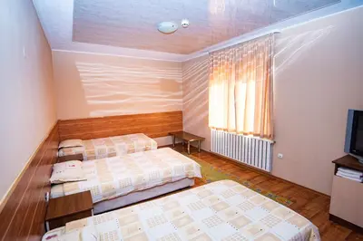 a hotel room with two beds and a television at Семеен Хотел Надежда in Razlog