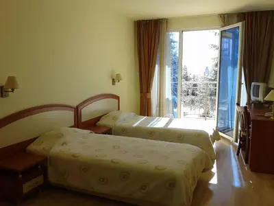 two beds in a hotel room with a window at Hotel Astrea in Hisarya