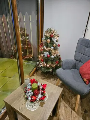 a christmas tree in a living room with a table at Юндовата къща in Beli Iskar