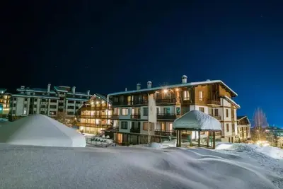 a large building in the snow at night at Green life Bansko, 1 bedroom private apartment D4 in Bansko