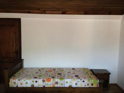 a bedroom with a bed and a white wall at Ristevata Guest House in Kovachevitsa