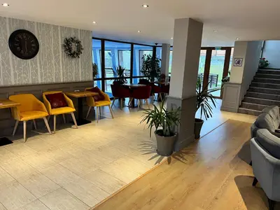a lobby with chairs and tables and a clock on the wall at Wood Apartment in Mountain View Complex in Bansko