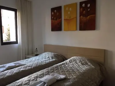 a bedroom with two beds and some pictures on the wall at Fortuna Complex Alexander Services Apartments in Bansko