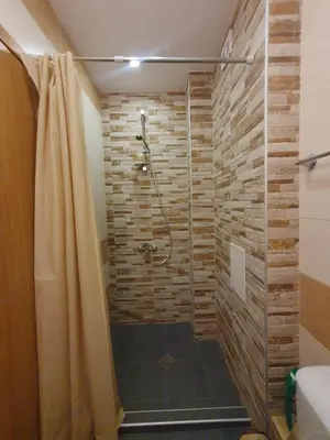 a bathroom with a shower with a stone wall at Mechka ski apartment in Bansko