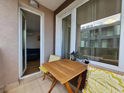 a wooden table and chairs on a balcony with a window at Brand new apartment with free parking near city center in Sofia