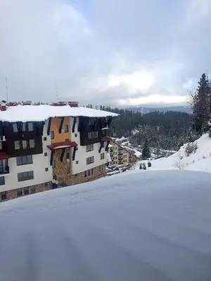 a snow covered hill in front of a building at Grand Monastery Deluxe Pamporovo 5 B 3 in Pamporovo