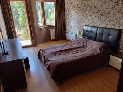 a bedroom with a bed and a desk and windows at Стаи и апартаменти под наем in Borovets