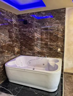 a white bath tub in a bathroom with tiles at Hotel Diamant in Dospat