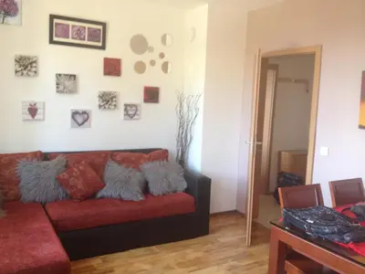 a living room with a red couch and pictures on the wall at Bansko ski apartment Mountain View Resort in Bansko