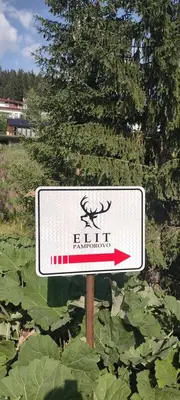a white sign with a red arrow in a field at Тайната квартира - The Secret apartment in Pamporovo