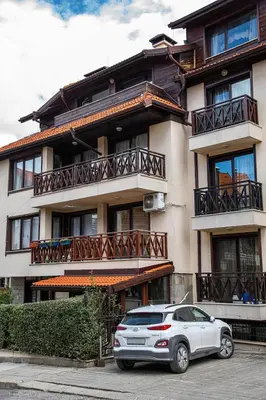 a white car parked in front of a building at Bansko Ski Apartment in Bansko