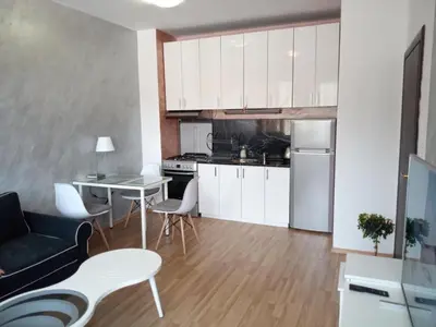 a kitchen and living room with white cabinets and a table at Апартамент Лукс в Спа Хотел Свети Спас in Velingrad