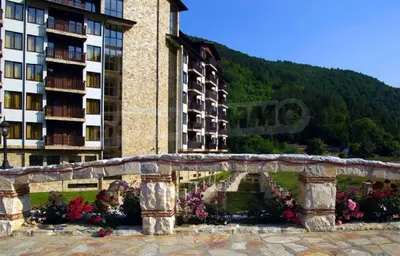 a stone bridge in front of a building with flowers at Апартамент Лукс в Спа Хотел Свети Спас in Velingrad