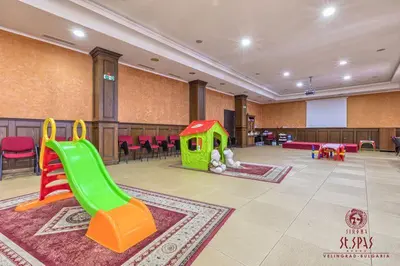 a childrens play area with a green slide and chairs at Апартамент Лукс в Спа Хотел Свети Спас in Velingrad