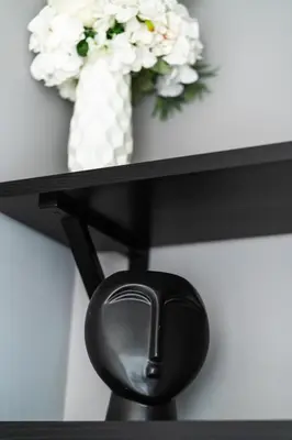 a black shelf with a vase with white flowers on it at Modern Apartment 2 with Parking next to Bulgaria Mall in Sofia